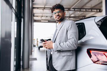 Business man choosing a car in car salon and talking on the phone
