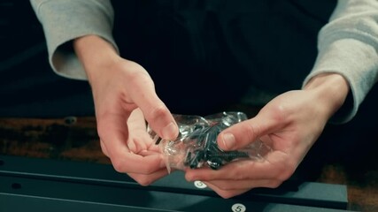 Teenager inspecting pack of bolts, preparing components for furniture assembly. Craftsman hands adjusting home fixtures. Performing fixing or improvement tasks