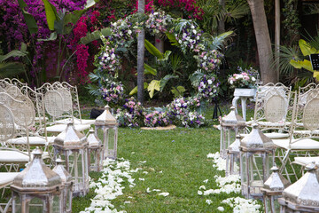 View of the walk down the aisle at an uncrowded outdoor wedding. Photo taken from the back, in the background arch of flowers and chairs for the guests and bride and groom.