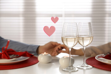 Couple holding hands during romantic dinner at home, closeup. Drawn hearts near them