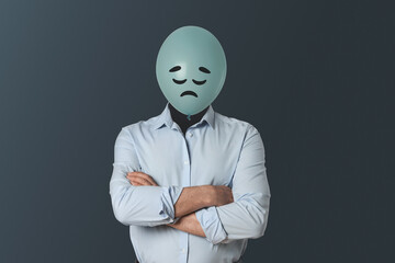 Balloon with sad face instead of man's head on dark grey background