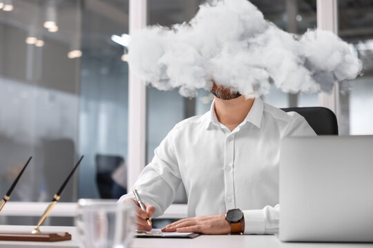 Businessman with cloud instead of head at table in office. Mental health