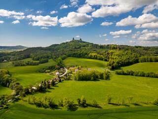 Obraz premium Aerial view of Trosky Castle with towers Baba and Panna rising above the green landscape of forests and meadows, a famous and popular historical site in the Czech Republic