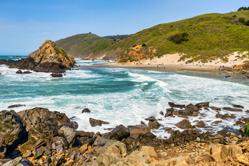 Stunning coastal landscape along California's Highway 1, featuring rugged rocky formations, and the vast blue ocean. A breathtaking natural scene showcasing the raw beauty of the Pacific coastline