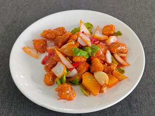 sweet and sour pork with green red peppers and pinapples in the white plate for eating
