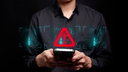 A person in a black shirt is typing on a mobile phone with a futuristic screen displaying a red exclamation symbol, indicating a cyber threat or hacking attempt.