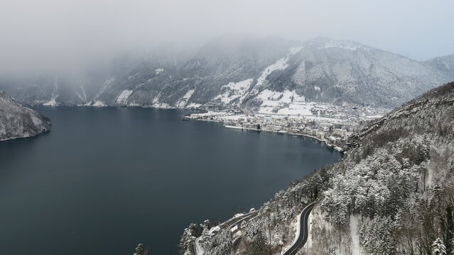 Fototapeta Stunning winter scene of a town nestled beside a snow-covered lake and mountains. Perfect for travel and winter backgrounds.