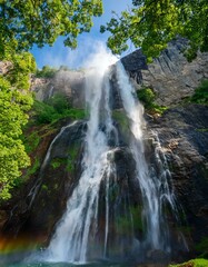 Obraz premium A stunning waterfall cascading down a rocky cliff surrounded by lush greenery.