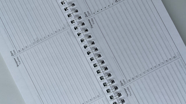 Minimalist close-up of an open spiral-bound weekly planner featuring days of the week in both Russian and English. 