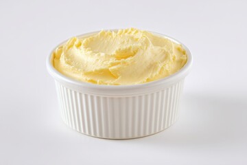 A ramekin of creamy, pale yellow butter sits on a white background.