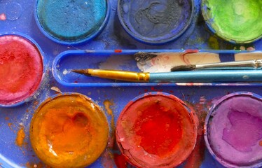 Multicolored water color palette with brushes close macro details art background