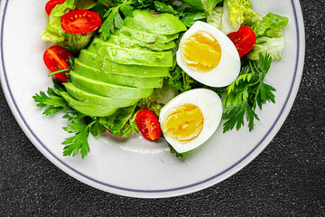 Avocado salad, boiled egg, tomato, green leaf lettuce, vegetable dish fresh delicious gourmet food background on the table rustic food top view copy space keto and paleo diet vegetarian food