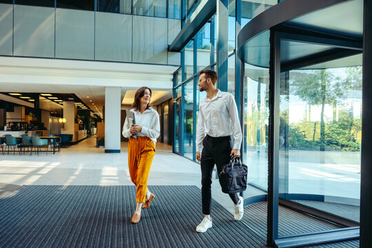 Coworkers arriving at modern office building entrance - Powered by Adobe