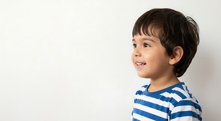 Portrait of adorable smiling little boy looking away with striped shirt on white background side view photo