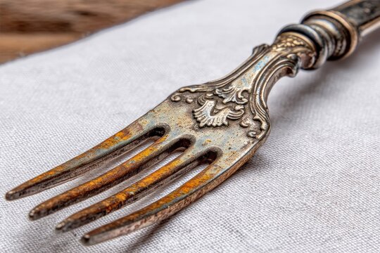 Rustic antique fork on linen fabric showcasing intricate details and worn finish in a warm, inviting setting
