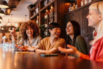 Cheerful female friends laughing and enjoying time together in cafe