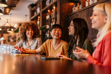Four young women laughing and talking in a restaurant