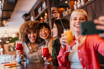 Cheerful female friends taking selfie while enjoying drinks at bar