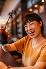Happy woman toasting with soft drink in cafe bar
