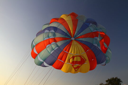 KARON, PHUKET, THAILAND - 30 APRIL 2025: Tourists relax on beautiful karon beach. Vacationers on Thailand Beach watch the sunset and ride a parasail.