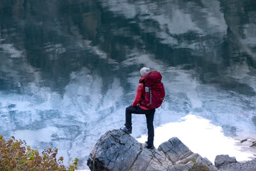Sporty girl looking into reflection of mountains in lake. Lake Oeschinensee in Swiss alps. Travel, adventure, healthy lifestyle, wanderlust concept.