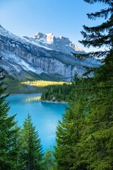 Amazing view of Switzerland Oeschinensee. Turquoise blue alpine lake amidst the snow capped mountains. Summer sunny day in Swiss Alps. Great tourist attraction for active sport and hiking