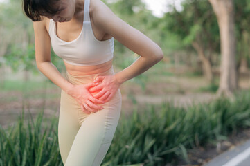 Asian woman experiencing injury and pain in exercise, holding her side with discomfort in outdoor...