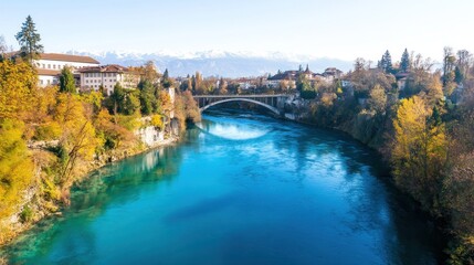 Obraz premium Stunning Autumnal River Scene in Switzerland: Bridge, Turquoise Waters, and Mountain Views