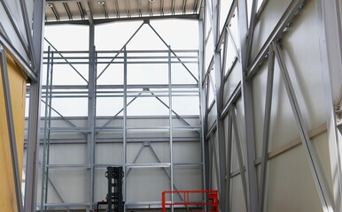 Modern frame structure and empty shelving system.Industrial warehouse interior with metal shelving and steel wall structure illuminated by natural sunlight.