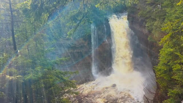 Miners Falls at Pictured Rocks National Lakeshore in Michigan during sunrise with cascading water and glowing forest scenery.