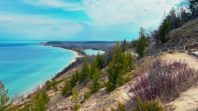 Breathtaking Sleeping Bear Dunes along Lake Michigan on a sunny summer day. The sweeping sandy dunes, turquoise water, and lush shoreline represent the natural beauty and adventure of Norther
