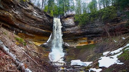 Munising Falls cascading down rock cliffs surrounded by forest at Pictured Rocks National Lakeshore in Michigan.