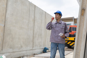 A construction manager in a safety helmet inspects a building site