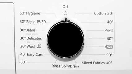 A close-up on washing machine control panel with a mechanical knob. knob labeled with program options such as off, Cotton, Delicates, Wool, Jeans, and Rapid Wash.