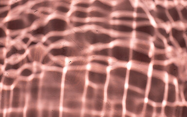 Mediterranean pink terracotta color plaster background with under water sun shadows.