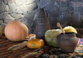 pumpkins and a clay pot, on a bench covered with a hand-woven carpet
