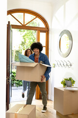 Young diverse couple carrying boxes into new home, smiling and excited for fresh start