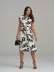 Fashionable woman in a floral dress posing elegantly in a modern studio
