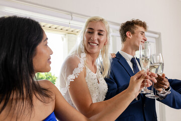 Bride and guests toasting with champagne, celebrating joyful wedding moment indoors