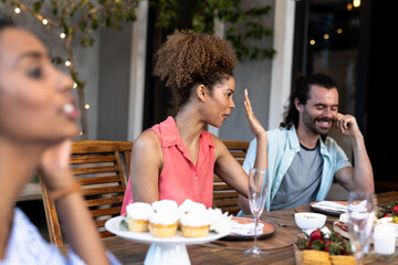 Diverse friends enjoying outdoor dinner party with cupcakes and lively conversation