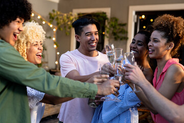 Diverse friends celebrating together, clinking glasses and smiling at outdoor party