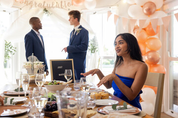 Woman in blue dress talking at wedding reception with two men in suits
