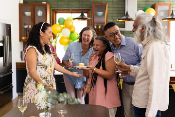 Celebrating birthday at home, diverse seniors laughing and drinking wine together