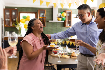 Celebrating birthday, senior friends with cake and wine in cozy home setting