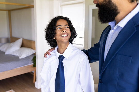 Diverse family, Father and son in formal attire smiling together at home, sharing joyful moment