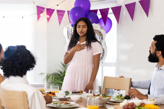 Giving speech at diverse family gathering, daughter celebrating special occasion, at home