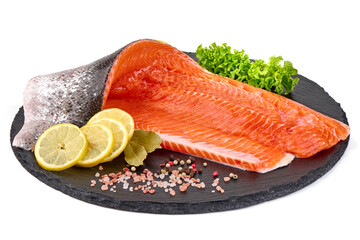 Raw Atlantic salmon fillet with skin and green lettuce on slate, isolated on white background.