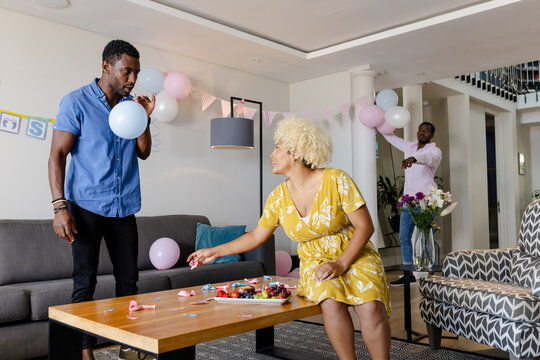 Friends decorating living room with balloons and ribbons for party celebration