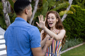 Naklejka premium Young couple outdoors, woman joyfully surprised, gesturing with hand, man smiling