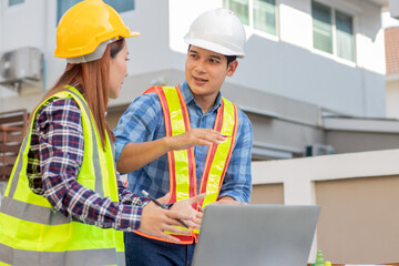 Male and female engineers wearing hard hats discuss blueprints in a house, demonstrating teamwork,...